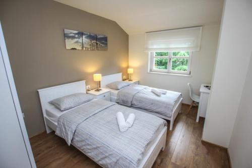 a bedroom with two beds with white sheets and a window at Apartment Doris in Poreč