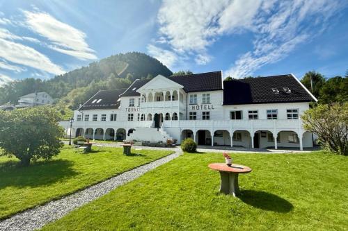 a large white building with a table in the grass at Tørvis Hotell in Luster