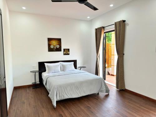 a bedroom with a bed and a sliding glass door at Hoa Cau HoiAn in Cam Thanh