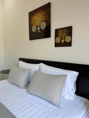 a bed with white pillows and two pictures on the wall at Hoa Cau HoiAn in Cam Thanh