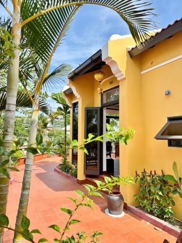 a yellow house with palm trees in front of it at Hoa Cau HoiAn in Cam Thanh