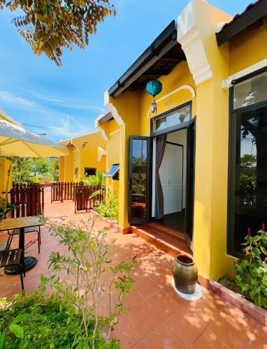 a yellow house with a patio and a table at Hoa Cau HoiAn in Cam Thanh
