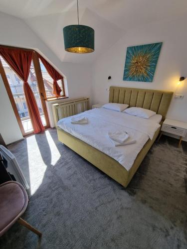 a bedroom with a large bed in a room with windows at Vila Alex in Tăşnad