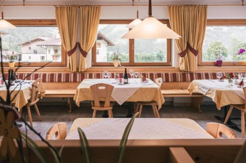 a restaurant with tables and chairs and windows at Pension Wiesenhof in Campo di Trens