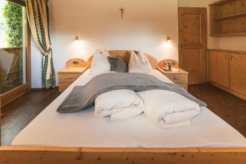 a large bed with white sheets and pillows on it at Pension Wiesenhof in Campo di Trens