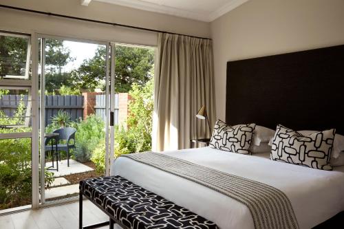 a bedroom with a large bed and a balcony at Brahman Hills - Gardens, Hotel & Cottages in Nottingham Road