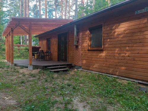 a cabin in the woods with a porch and a table at Domek nad jeziorem 7 in Kamienica Królewska
