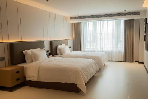 a hotel room with two beds and a window at Zhongshan Jiayue Hotel in Zhongshan