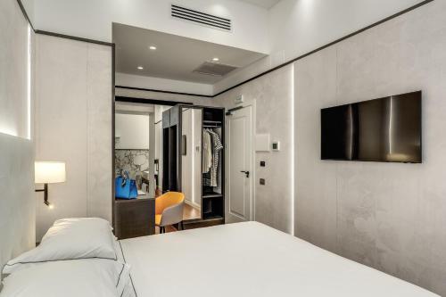 a bedroom with a white bed and a flat screen tv at The Spotlight Boutique Hotel in Rome