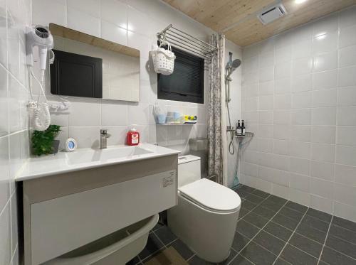 a white bathroom with a toilet and a sink at 糸旅行蹤 老宅民宿包棟 in Gukeng