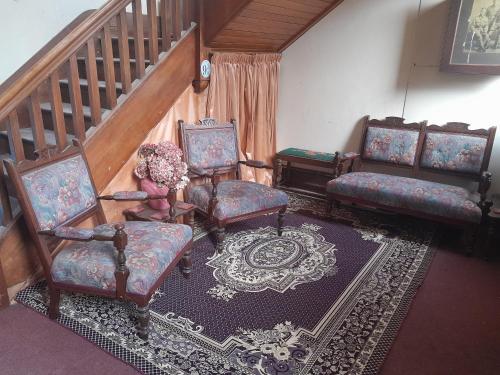 a living room with three chairs and a staircase at St David's on James Luxury apartments in Dunedin