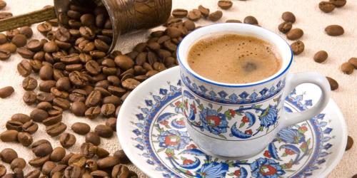 a cup of coffee on a plate next to coffee beans at Come again Coffee and Hostel in Jomtien Beach