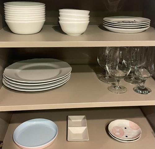 a shelf filled with plates and bowls and wine glasses at 糸旅行蹤 老宅民宿包棟 in Gukeng