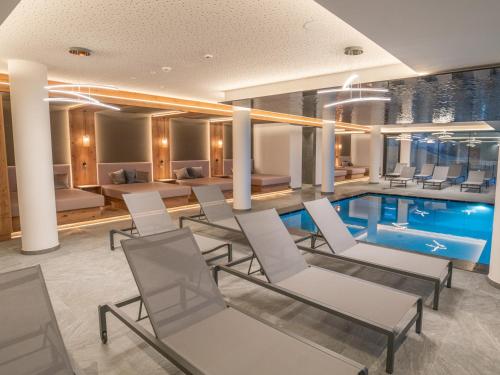 a pool in a hotel room with chairs and a table at Hotel Purvita by Oberlechner in Maranza