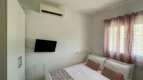 a bedroom with a bed with a tv on the wall at Mina’s house in Amarinthos