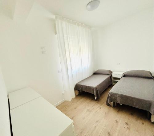 een kleine kamer met twee bedden en een raam bij Verga - Dietro Piazza Mazzini - Immobil Relax in Lido di Jesolo