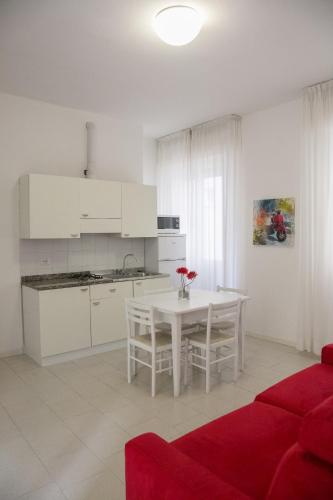 a white kitchen with a white table and chairs at Residence Villa Ofelia in Rimini