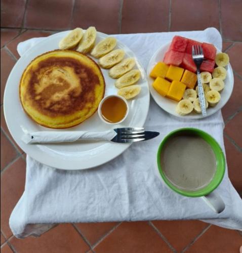 a plate with pancakes and fruit and a cup of coffee at Opera Premier Hotel in Luang Prabang