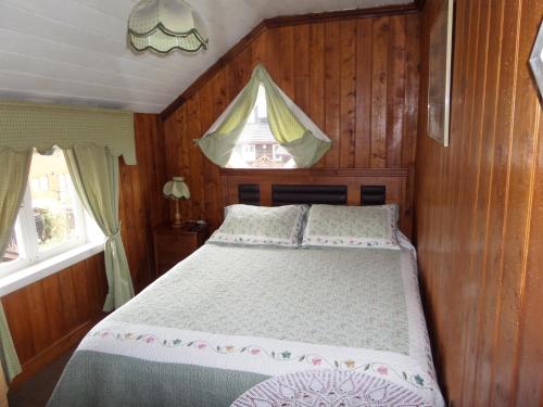a bedroom with a bed with wooden walls and a window at Hostal y Cabañas Villa Germana in Puerto Varas
