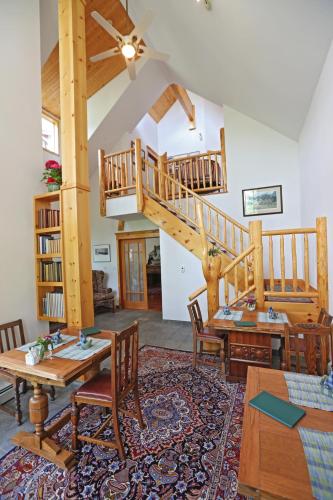 a living room with a staircase and wooden tables and chairs at Beaujolais Boutique B&B at Thea's House- Adults Only in Banff