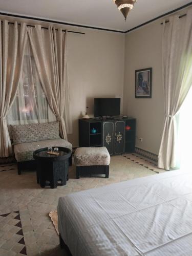 a bedroom with a bed and a couch and a tv at Villa Marrakchia - Palais d'hôtes & spa in Marrakech