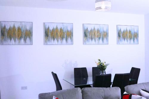 a dining room with a table and four paintings on the wall at A beautiful spacious brand-new 3 Bed Guest house in Oxford City - 10mins walk to Oxford Hospitals in Oxford