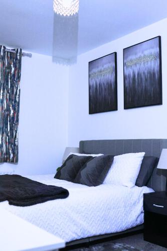 a bedroom with a bed with three pictures on the wall at A beautiful spacious brand-new 3 Bed Guest house in Oxford City - 10mins walk to Oxford Hospitals in Oxford