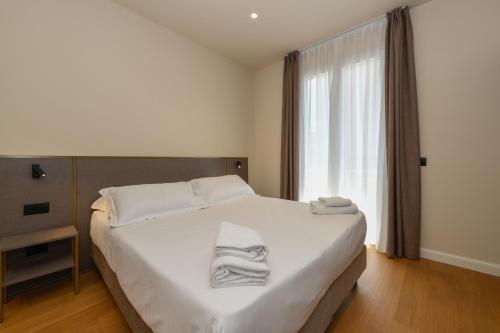 a bedroom with a white bed with towels on it at Hotel Arya by Mauro in Sirmione