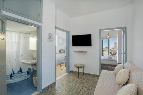 a living room with a couch and a tv and a bathroom at Mandilara Minimal Apartment in Rhodes Town