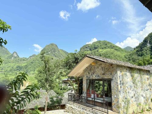a small building with mountains in the background at Du Gia NaLien View Homestay in Làng Cac