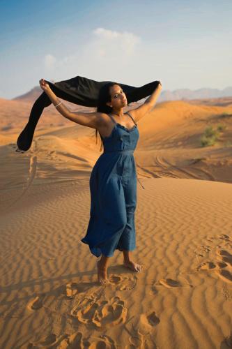 a woman in a blue dress standing in the desert at Erg Chebbi Dunes Desert Camp in Merzouga