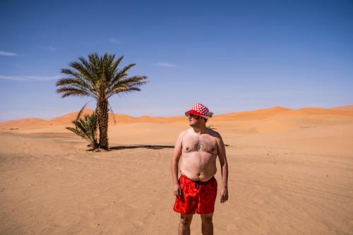 a man with a tattoo on his back standing in the desert at Erg Chebbi Dunes Desert Camp in Merzouga