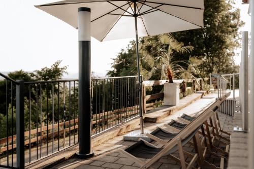 a group of chairs and an umbrella on a balcony at Die Triniushütte "Thüringens schönste Aussicht" in Rauenstein