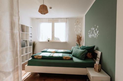 a bedroom with a bed with green sheets and a window at Die Triniushütte "Thüringens schönste Aussicht" in Rauenstein