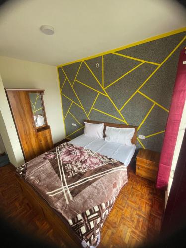 ein Schlafzimmer mit einem Bett mit einer gelben und schwarzen Wand in der Unterkunft Ooty Dream Weaver cottage in Udagamandalam