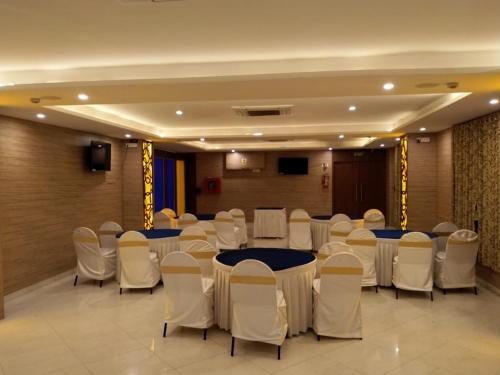 a banquet hall with tables and white chairs at T S Royal Grand Hotel in Bengaluru