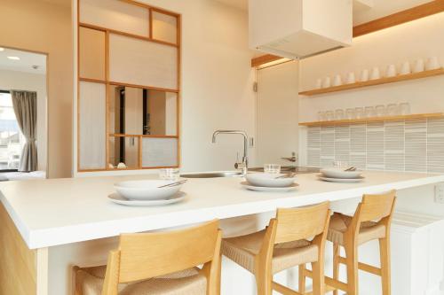 a kitchen with a large white island with chairs at Tokyo Sky Suite Hotel in Tokyo