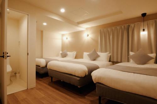 a hotel room with three beds and a window at LikeINN札幌スイーズS4 in Sapporo