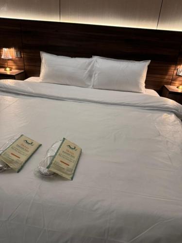 een wit bed met daarop twee certificaten bij ليالي طيبة in Al Madinah