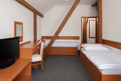 a room with two beds and a desk and a tv at Hotel Pohoda in Staré Město