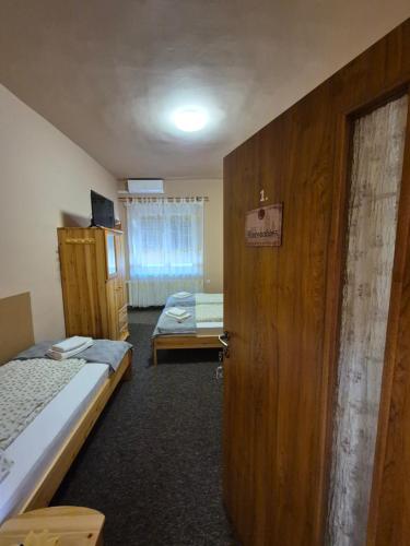 a room with two beds and a wooden door at Vár-Liget Vendégház in Kisnána