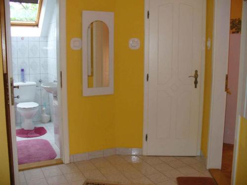 a bathroom with a toilet and a yellow wall at Caty Vendégház in Hajdúszoboszló