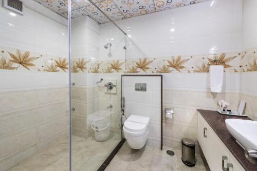 a bathroom with a shower and a toilet and a sink at T S Royal Grand Hotel in Bengaluru