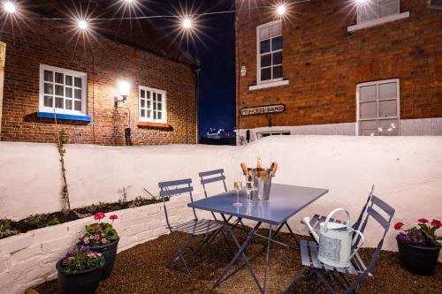 a blue table and chairs on a patio at night at Bronte's Rest - Detached Elegant Cottage in Historic Old Town with Garden in Scarborough