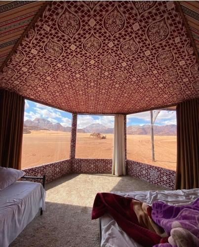 DisahにあるCamp tala moonの砂漠の景色を望む大きな窓付きのベッドルーム1室