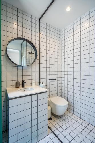 a white tiled bathroom with a sink and a toilet at Bright & Central 2BR in Historic Heart of Sofia in Sofia