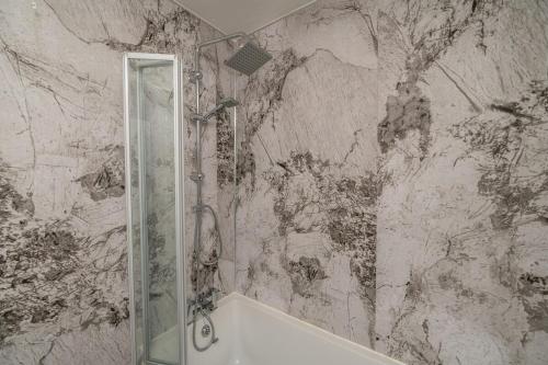 a bathroom with a shower and a marble wall at Contractor & Family Full House NEC Bhm Airport Netflix Coffee in Olton