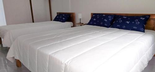 a bedroom with two white beds with blue pillows at Leribi Suites and Restaurant in Ulot