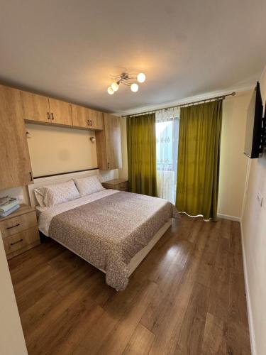a bedroom with a bed and a window with green curtains at La Pop Cu Drag in Ocna Şugatag