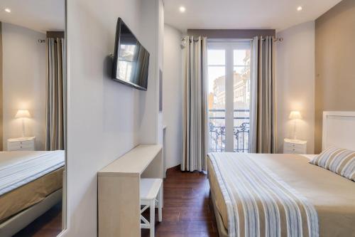 a hotel room with two beds and a window at Hotel Lepante in Nice